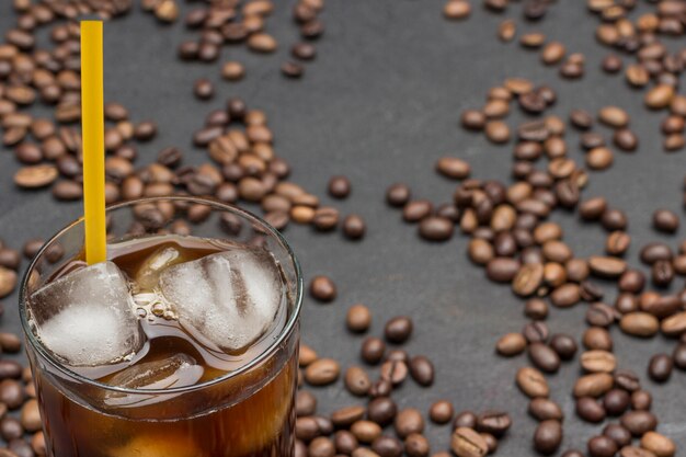 IJsblokjes in glas met koffie en geel stro.