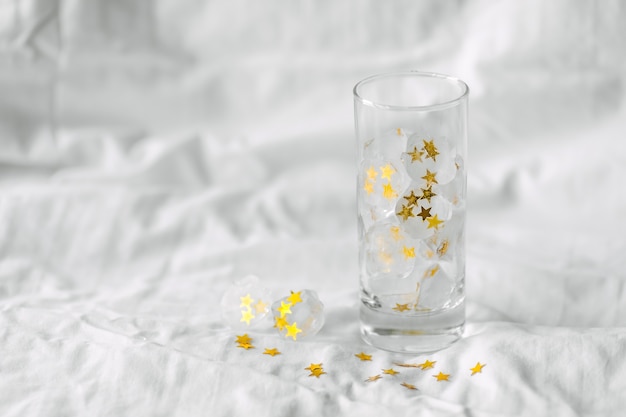 IJsblokjes met bevroren gouden sterren in een glas water