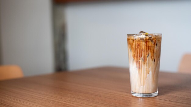 Foto ijskoffie in een glas op houten tafel en witte muurachtergrond