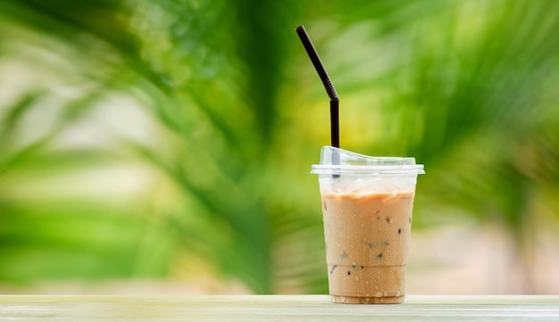 Ijskoffie in hoge glazen ijsblokjes koel zomerdrankje met rietjes op warme natuurlijke groene wazige achtergrond kopieerruimte