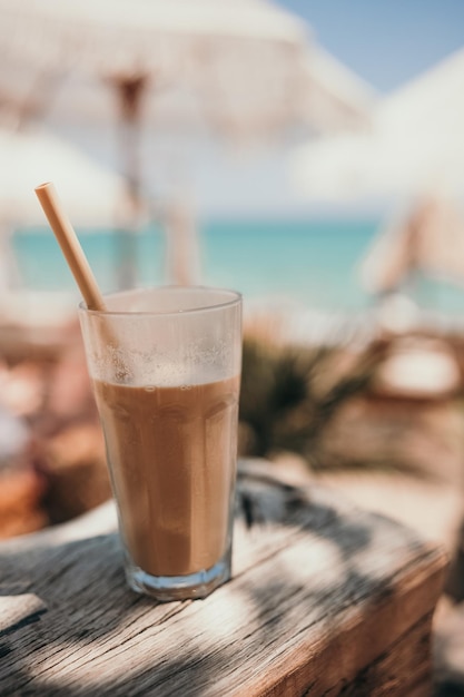 IJskoffie latte in hoog glas met stro aan zee in strandbar