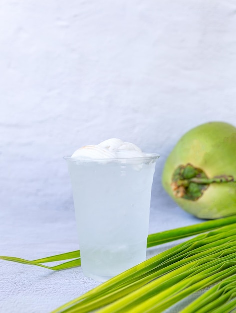 IJskokosnootwaterdrank in een plastic glas en kokosnoot op witte achtergrond