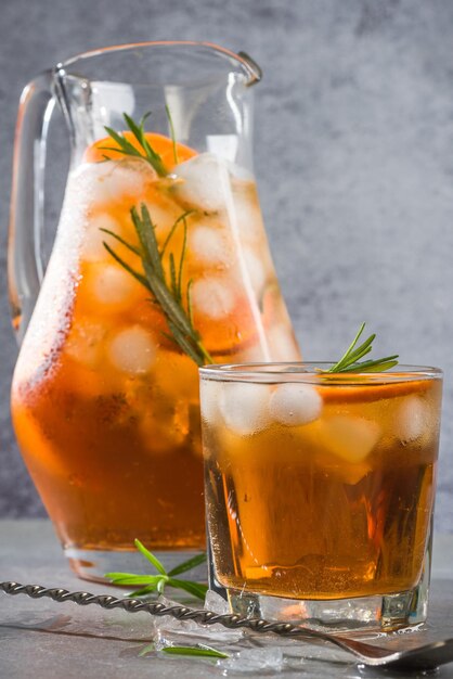 Foto ijskoude thee in kan en glas met rozemarijn garnituur