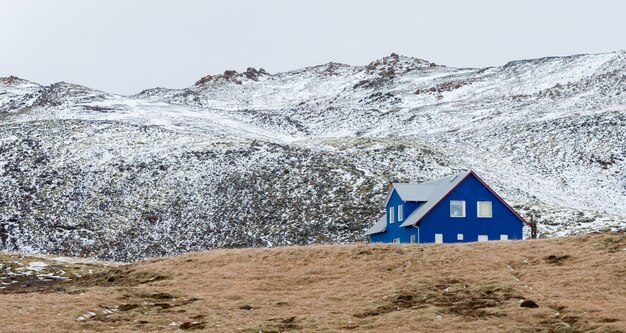 IJslands landschap met blauw chalet boerderij huis bergen bedekt met sneeuw in de lente IJsland