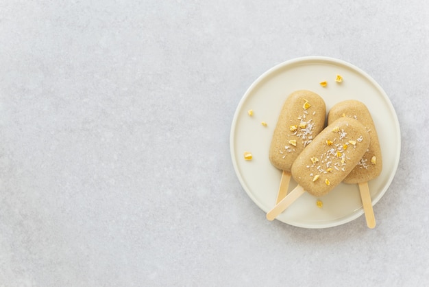 Ijslolly met stukjes chocolade cashewnoten, mango en kokos op een bord