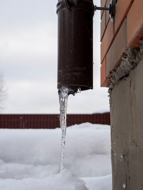 IJspegel steekt uit de regenpijp Na een hevige sneeuwstorm is de stad bedekt met sneeuw en ijs