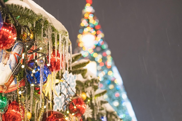 IJspegels op een versierde tak tegen de achtergrond van een kerstboom