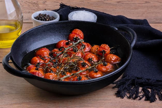 IJzeren braadpan met gekonfijte tomaten op houten tafel.