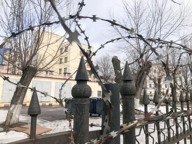 IJzeren metalen scherpe gevaarlijke beschermende prikkeldraad op het hek met spikes en staken tegen de lucht