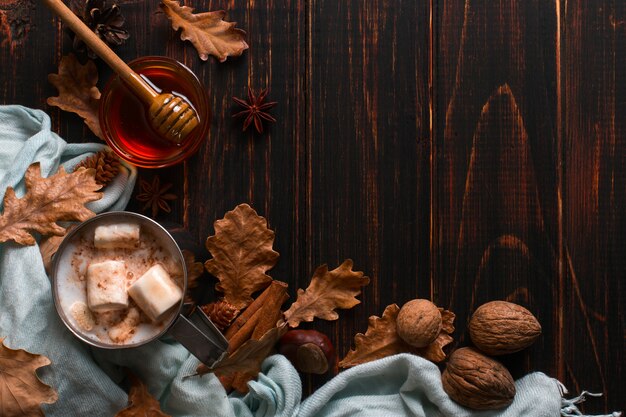 IJzeren mok met cacao, honing, marshmallows, kruiden, op een achtergrond van een sjaal, droge bladeren op een houten tafel. Herfststemming, een warm drankje. copyspace.