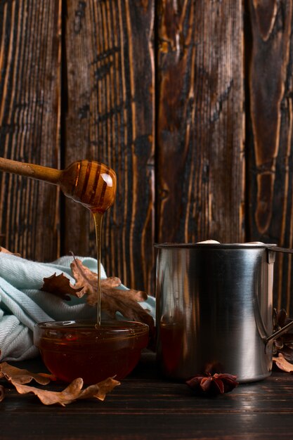 IJzeren mok met cacao, honing, marshmallows, kruiden, op een achtergrond van een sjaal, droge bladeren op een houten tafel. Herfststemming, een warm drankje. copyspace.