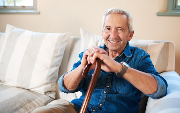 Ik ben goed en zo is het leven portret van een senior man die thuis zit met een wandelstok