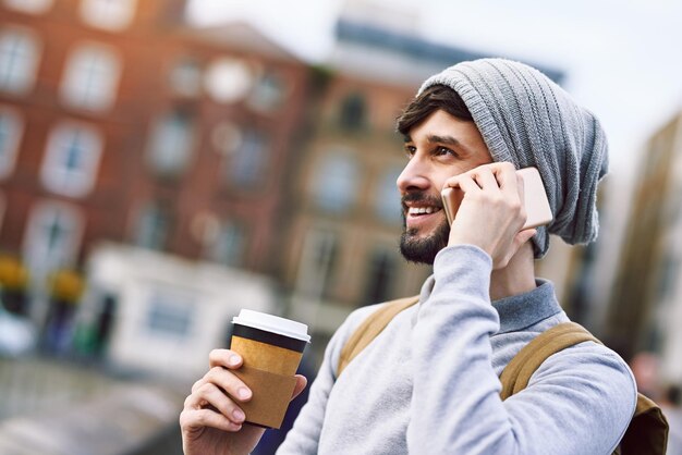 Ik ben in je nek van de buurt Shot van een jonge man die zijn mobiele telefoon gebruikt terwijl hij in de stad is