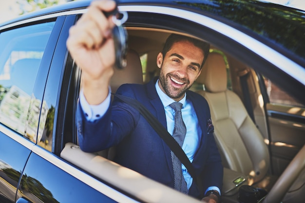 Ik ben op weg naar een belangrijke vergadering Portret van een vrolijke jonge zakenman die de camera vasthoudt terwijl hij in zijn auto zit