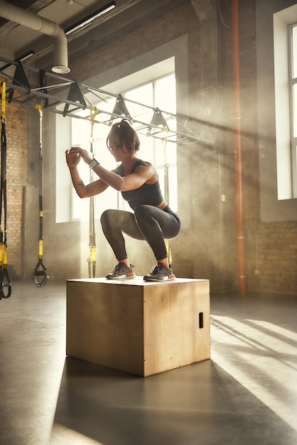 Ik daag mezelf uit zijaanzicht van een atletische vrouw in sportkleding die squat doet terwijl ze op een houten ondergrond staat