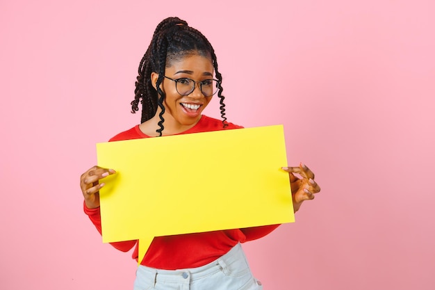 Ik denk peinzende afro-vrouw die naar een lege tekstballon kijkt en haar kin kopieerruimte roze studiomuur aanraakt