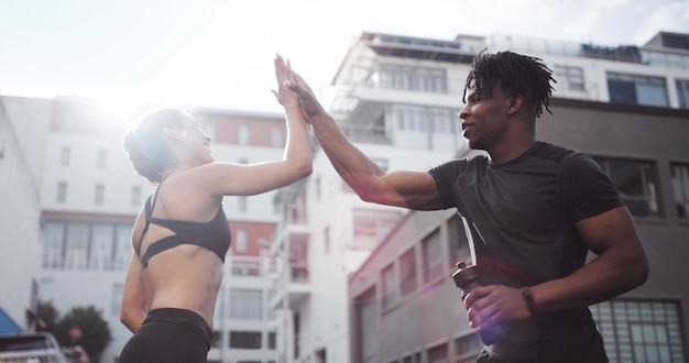 Ik geloof in jou Shot van een jong stel dat elkaar een highfive geeft terwijl ze buiten in sportkleding staan