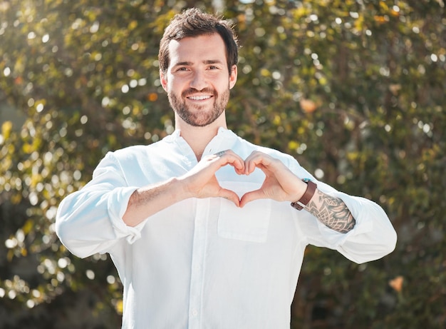 Foto ik heb alles over liefde. bijgesneden portret van een knappe jongeman die een hartvorm maakt met zijn handen buitenshuis.