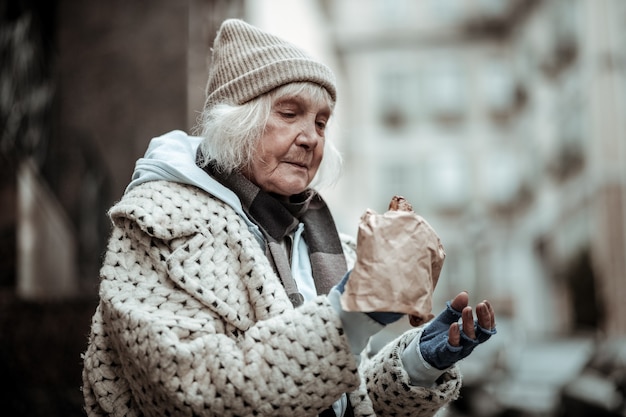 Ik heb honger. Trieste oude vrouw die naar het eten kijkt terwijl ze erg honger heeft