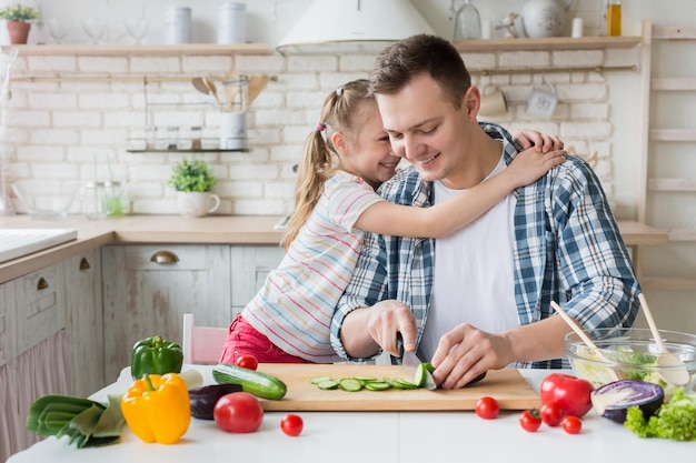 Ik hou van je papa. Mooi meisje knuffelt vader terwijl de man een gezond diner kookt, kopieer ruimte