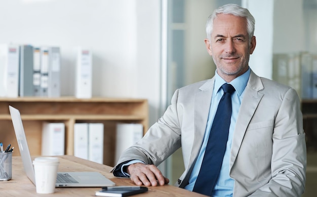 Ik hou van mijn werk Een manager zit aan zijn bureau en lacht naar de camera