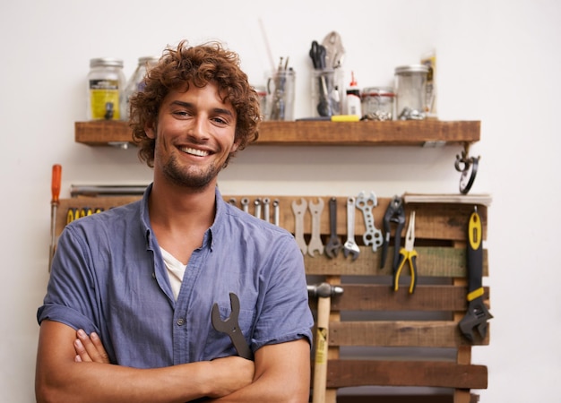 Ik kan alles repareren Een jonge man die voor zijn gereedschap in de garage staat