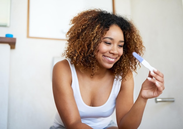 Ik kan niet wachten om het goede nieuws te delen Shot van een jonge vrouw die naar de resultaten van haar zwangerschapstest kijkt