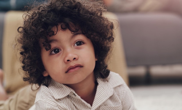 Ik vraag me af of er nog snacks over zijn. shot van een schattig jongetje dat op een tapijt ligt en thuis tv kijkt