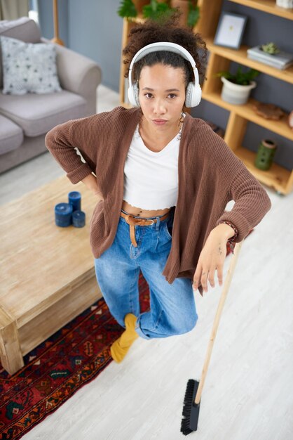 Ik wacht tot het volgende nummer begint voordat ik weer ga schoonmaken Shot van een vrouw die een koptelefoon draagt terwijl ze thuis bezig is met schoonmaken