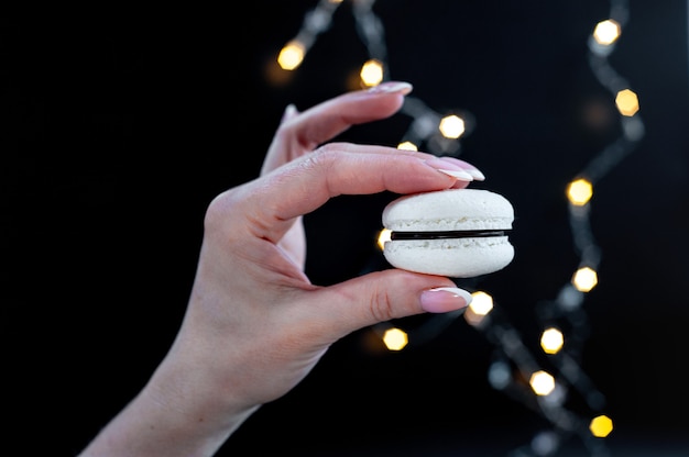 Foto ik wil bitterkoekjes, vrouwelijke hand houdt bitterkoekjes op zwarte achtergrond