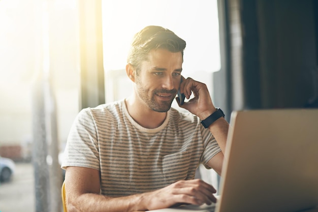 Ik zal contact met je opnemen Een jonge man aan de telefoon terwijl hij met zijn laptop in een coffeeshop zit