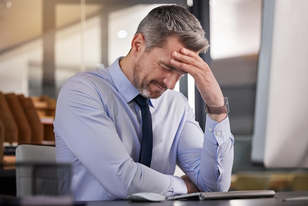 Ik zou vandaag wat extra motivatie kunnen gebruiken Shot van een zakenman die hoofdpijn heeft terwijl hij aan zijn bureau zit