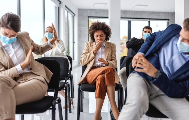 Imprenditrice malata tosse mentre era seduto con i suoi colleghi in seminario. i colleghi hanno paura del coronavirus, quindi si nascondono.