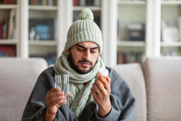 Photo ill man covered in blanket reading sticker on medicine jar