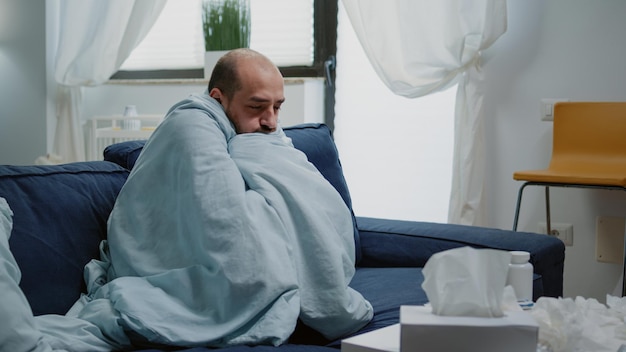 Ill man sitting on sofa at home