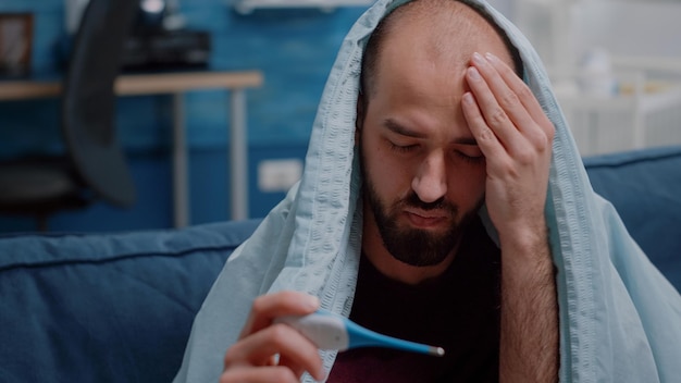 Ill man sitting on sofa at home