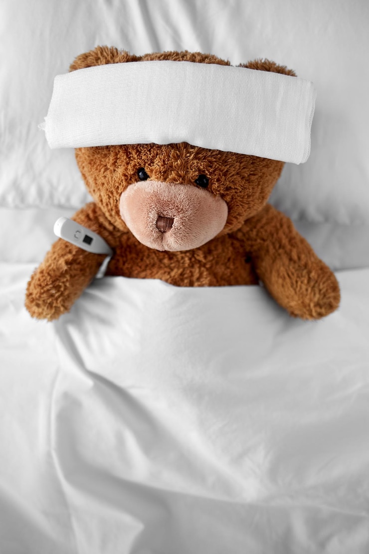 Photo ill teddy bear with bandage and thermometer in bed