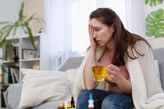 Больная женщина пьет горячее лекарство, растворимый порошок в стакане воды