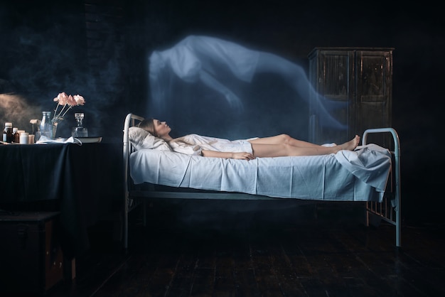 Фото Больная женщина лежит на больничной койке, душа покидает тело