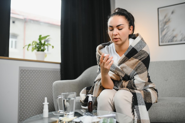 Ill woman using nasal spray at home