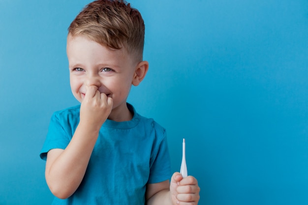 Ill young child with a thermomether, measuring the height of his fever 