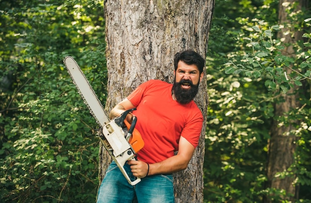 Photo illegal logging continues today lumberjack in the woods with chainsaw axe lumberjack on serious face