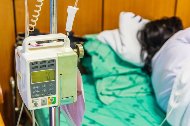 Illness asian old woman lying on sickbed in hospital with infusion pump intravenous IV dri