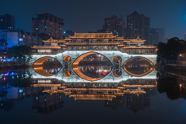 Foto ponte ad arco illuminato sul fiume in città di notte