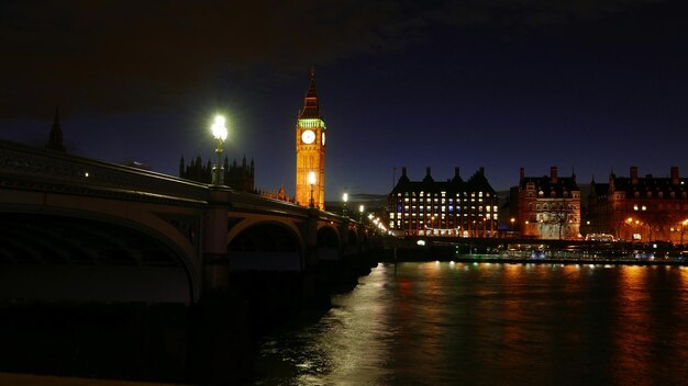 Illuminated big ben by river thames at night