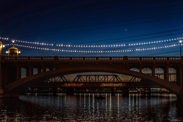 Photo illuminated bridge over calm river at night