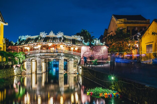 Illuminated bridge over canal amidst buildings in city at night