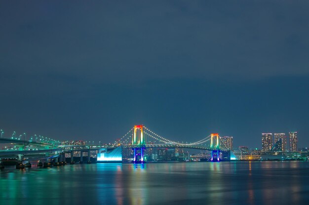 写真 川を横断する照らされた橋と背景の都市