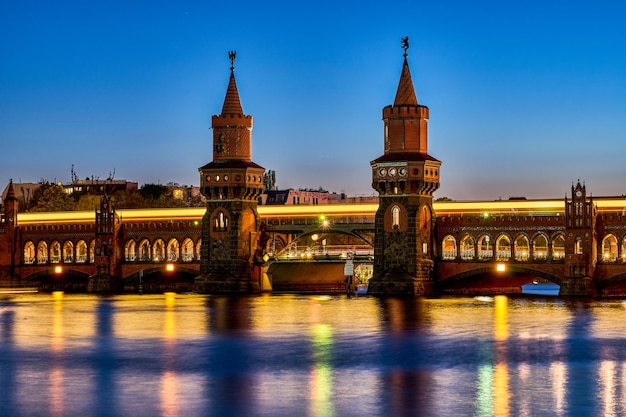 Illuminated bridge over river against blue sky in city