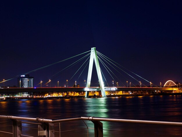 Illuminated bridge over river against clear sky at night